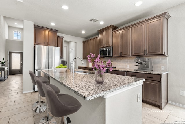 2126 Elysian, San Antonio, TX 78253 - kitchen featuring stainless steel appliances, a sink, tasteful backsplash, a kitchen island with sink, and light stone counters
