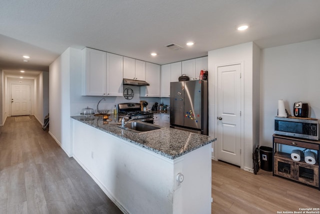 3823 Casado, Converse, TX 78109 - kitchen with stainless steel appliances, under cabinet range hood, dark stone counters, light wood-style floors, and recessed lighting