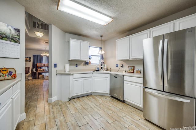 1027 Hedgestone, San Antonio, TX 78258 - kitchen featuring stainless steel appliances, a textured ceiling, light countertops, white cabinets, and a chandelier
