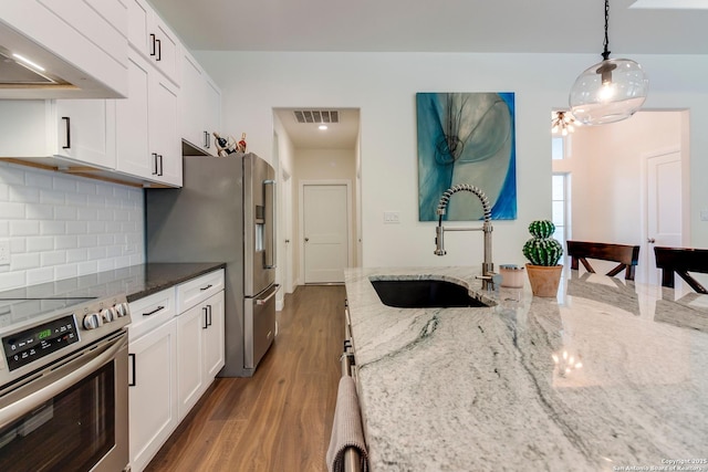 224 Frey, Boerne, TX 78006 - kitchen with stainless steel appliances, a sink, wall chimney exhaust hood, tasteful backsplash, and white cabinets