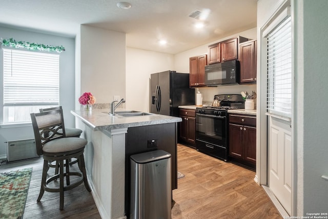 14718 Fronted Goose, San Antonio, TX 78253 - kitchen with black appliances, a sink, a kitchen breakfast bar, and light wood finished floors