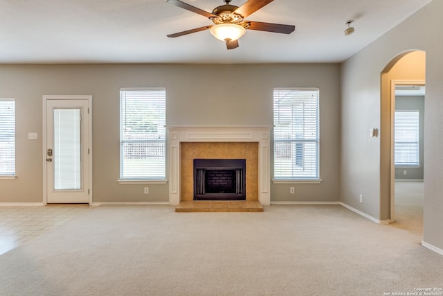 109 Sage Cyn, Boerne, TX 78006 - unfurnished living room with arched walkways, a ceiling fan, a tiled fireplace, baseboards, and carpet