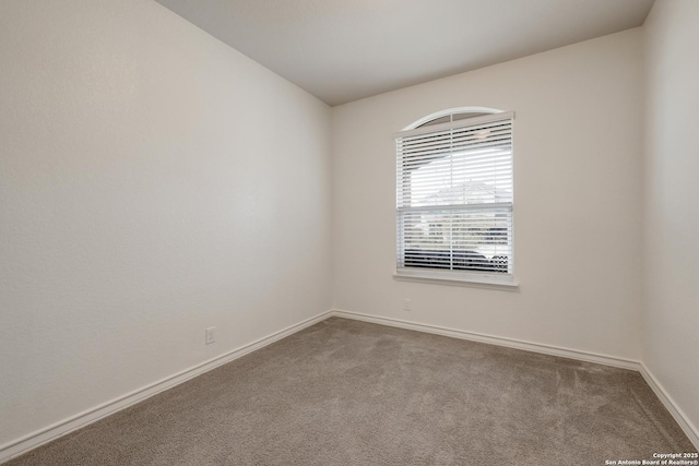 carpeted spare room featuring baseboards