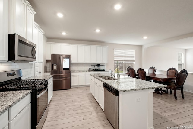 kitchen with appliances with stainless steel finishes, healthy amount of natural light, light wood-style floors, a sink, and recessed lighting