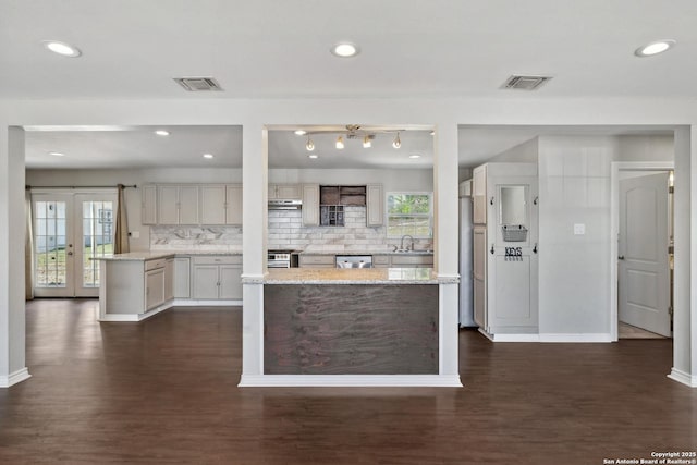 kitchen with dark wood-style floors, stainless steel dishwasher, baseboards, tasteful backsplash, and recessed lighting