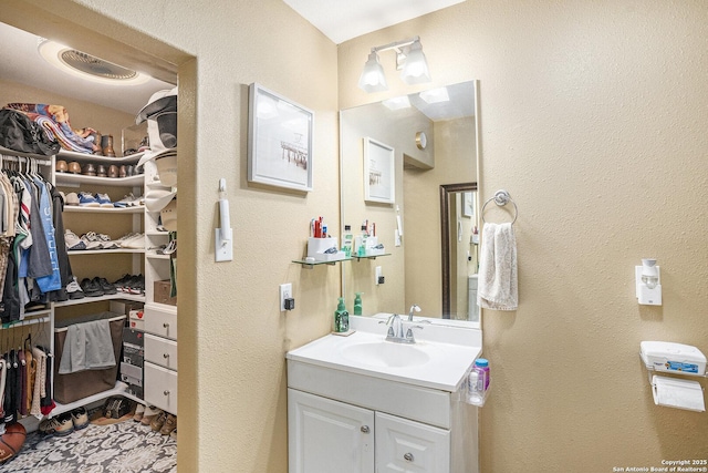 715 E Southcross, San Antonio, TX 78214 - bathroom with a spacious closet, vanity, and a textured wall