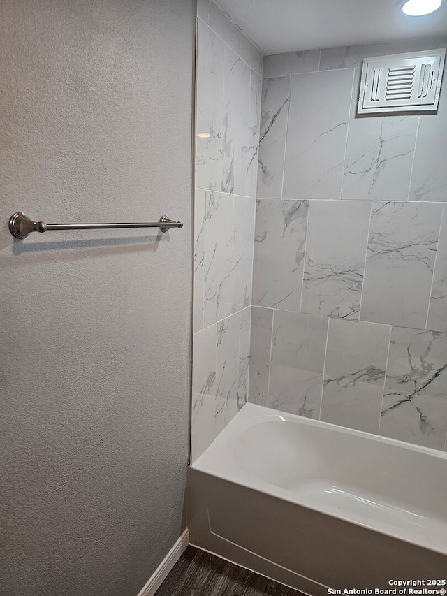 110 Heather Ave, San Antonio, TX 78223 - bathroom with wood finished floors, baseboards, a textured wall, and shower / bathtub combination