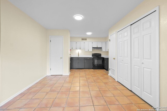 6123 Farragut, San Antonio, TX 78238 - kitchen featuring black electric range oven, light countertops, white cabinetry, light tile patterned floors, and baseboards