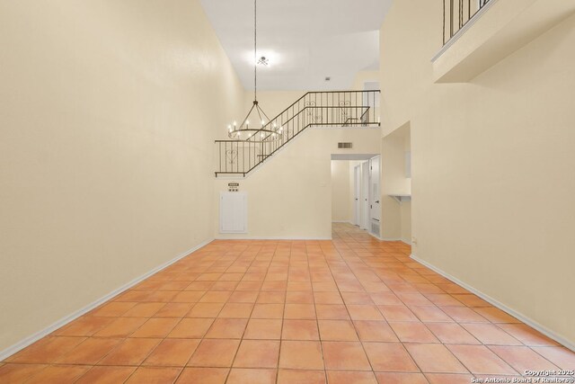 6123 Farragut, San Antonio, TX 78238 - unfurnished living room with a towering ceiling, a chandelier, light tile patterned flooring, and baseboards