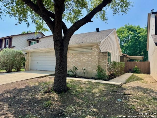 5739 Spring Moon, San Antonio, TX 78247 - view of front of house with brick siding, fence, an attached garage, and driveway