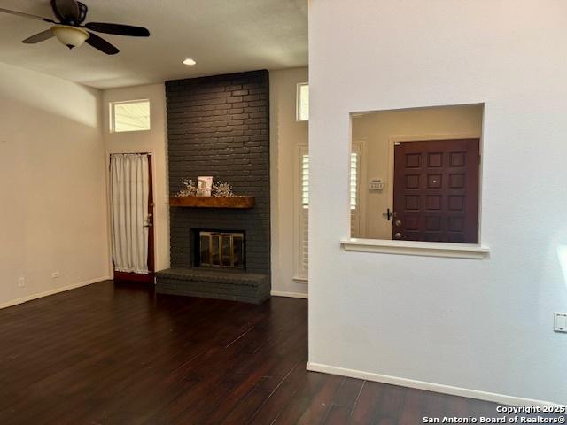 5739 Spring Moon, San Antonio, TX 78247 - unfurnished living room with wood finished floors, baseboards, a ceiling fan, and a brick fireplace