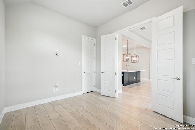355 Jereth, Castroville, TX 78009 - spare room with light wood-style floors, baseboards, a sink, and a chandelier