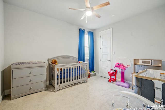355 Jereth, Castroville, TX 78009 - carpeted bedroom featuring baseboards, a ceiling fan, and a nursery area