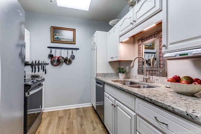 1 Towers Park Ln Unit 907, San Antonio, TX 78209 - kitchen featuring stainless steel appliances, a sink, light wood-style flooring, white cabinetry, and light stone countertops