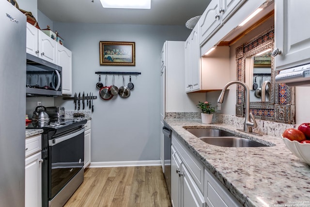 1 Towers Park Ln Unit 907, San Antonio, TX 78209 - kitchen featuring appliances with stainless steel finishes, a sink, light wood-style flooring, white cabinets, and light stone countertops