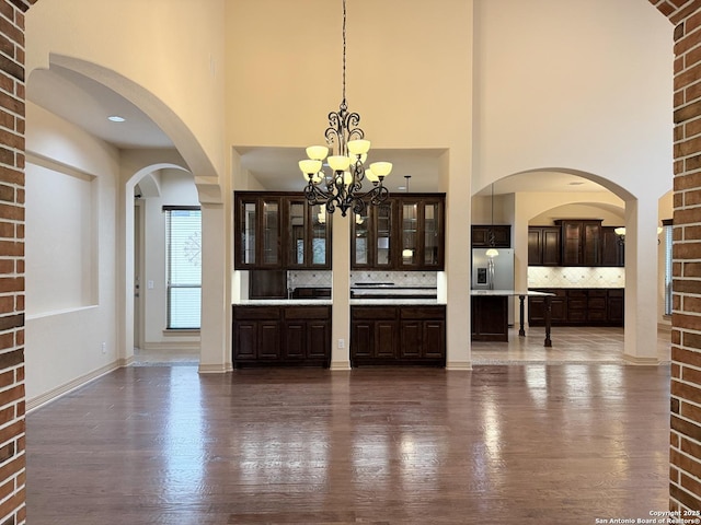 4419 Tapia, San Antonio, TX 78261 - bar area featuring decorative backsplash, stainless steel fridge, a high ceiling, dark wood-style floors, and decorative light fixtures