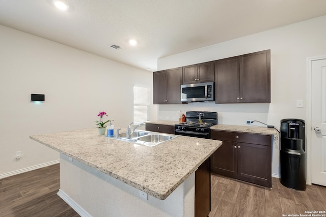 13915 Jasperoid, San Antonio, TX 78253 - kitchen with gas stove, a sink, stainless steel microwave, dark brown cabinetry, and dark wood-style flooring