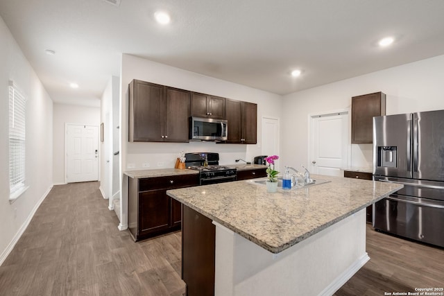 13915 Jasperoid, San Antonio, TX 78253 - kitchen with stainless steel appliances, a sink, dark brown cabinets, wood finished floors, and light stone countertops