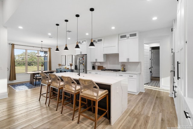 187 Stone Loop, Castroville, TX 78009 - kitchen with appliances with stainless steel finishes, light wood finished floors, a kitchen bar, an island with sink, and recessed lighting