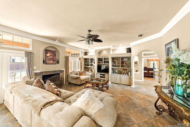 19114 Autumn, San Antonio, TX 78258 - living area featuring arched walkways, crown molding, a tile fireplace, a ceiling fan, and stone finish floors