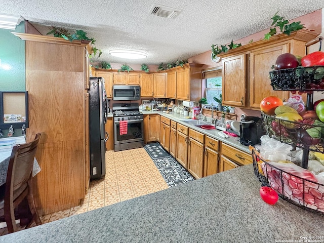 602 Hortencia Ave, San Antonio, TX 78237 - kitchen with appliances with stainless steel finishes, a sink, a textured ceiling, light countertops, and light floors