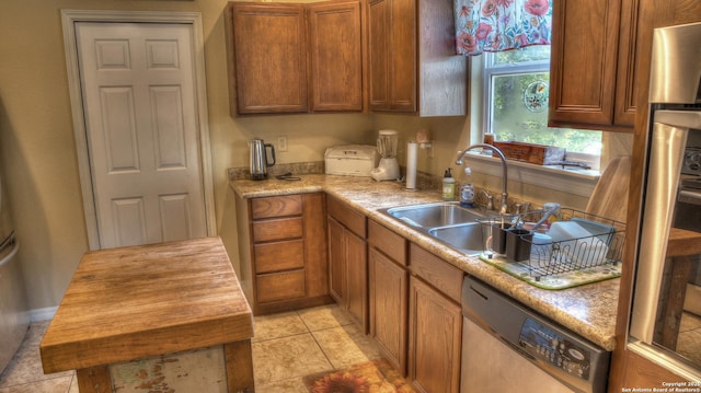 211 Roy Chisum Rd, Leakey, TX 78873 - kitchen with dishwasher, a sink, brown cabinetry, and light tile patterned flooring