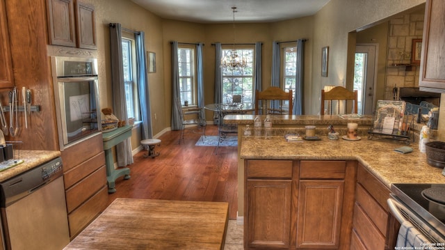 211 Roy Chisum Rd, Leakey, TX 78873 - kitchen with stainless steel appliances, brown cabinetry, light countertops, wood finished floors, and baseboards