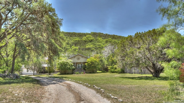 211 Roy Chisum Rd, Leakey, TX 78873 - view of front of property with a forest view, dirt driveway, a front lawn, and an outdoor structure