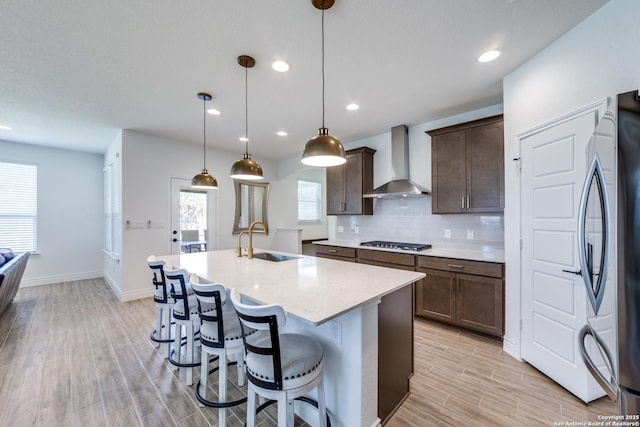 12531 Yancey, San Antonio, TX 78253 - kitchen featuring wall chimney range hood, stainless steel appliances, a sink, a center island with sink, and light wood-type flooring