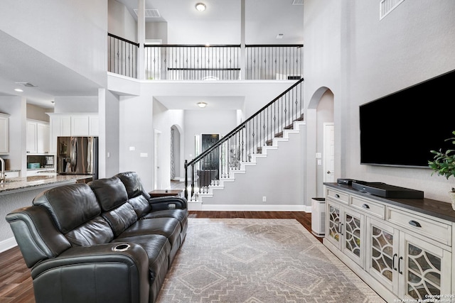 27210 Camellia, Boerne, TX 78015 - living area featuring arched walkways, a towering ceiling, dark wood finished floors, stairs, and baseboards