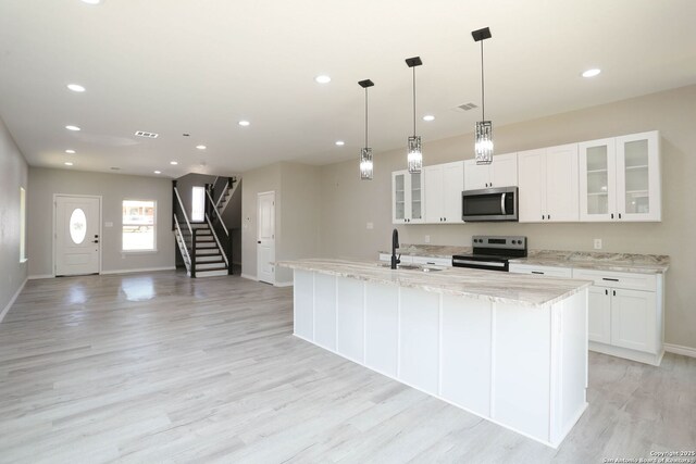 656 Canyon Cir, Canyon Lake, TX 78133 - kitchen featuring stainless steel appliances, a sink, light wood finished floors, baseboards, and white cabinetry
