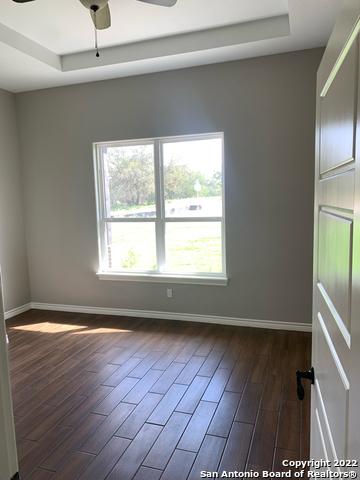 128 Woodbridge Ln, Vernia, TX 78121 - spare room with ceiling fan, dark wood-type flooring, a raised ceiling, and baseboards