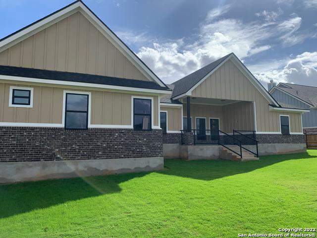 128 Woodbridge Ln, Vernia, TX 78121 - back of property featuring a lawn, board and batten siding, and brick siding