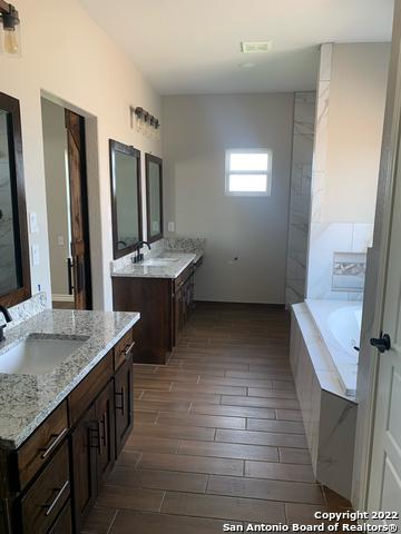 128 Woodbridge Ln, Vernia, TX 78121 - bathroom featuring wood tiled floors, a garden tub, and two vanities