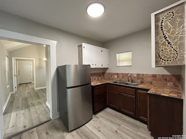270 Oelkers, San Antonio, TX 78204 - kitchen with freestanding refrigerator, a sink, tile counters, light wood finished floors, and white cabinetry