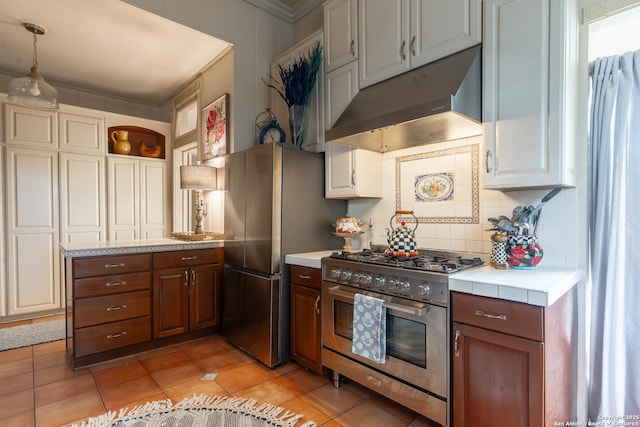 529 N High, Uvalde, TX 78801 - kitchen with stainless steel appliances, under cabinet range hood, open shelves, tasteful backsplash, and tile countertops