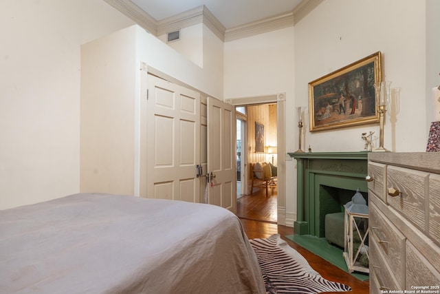529 N High, Uvalde, TX 78801 - bedroom featuring ornamental molding, wood finished floors, a fireplace with flush hearth, and a towering ceiling