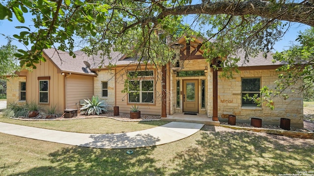 7881 Wegner, New Braunfels, TX 78132 - view of front facade with stone siding, a front yard, board and batten siding, and roof with shingles