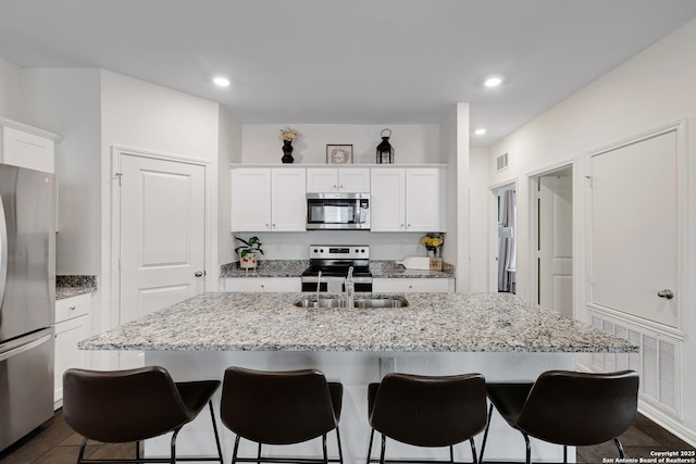 7910 Asp Pt, San Antonio, TX 78253 - kitchen with appliances with stainless steel finishes, a sink, a kitchen breakfast bar, white cabinets, and a center island with sink