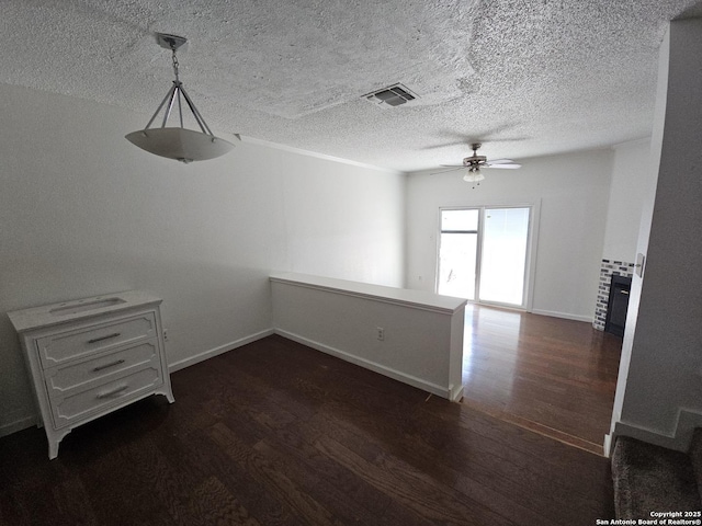 unfurnished dining area featuring dark wood-style floors, ceiling fan, a textured ceiling, and baseboards