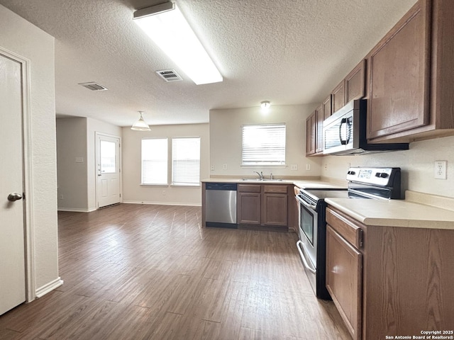 11023 Gilpin, Helotes, TX 78023 - kitchen featuring stainless steel appliances, light countertops, a textured ceiling, dark wood-style floors, and a sink