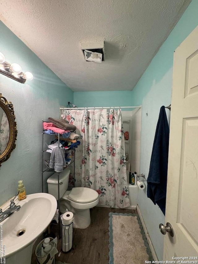 1702 Westmar, San Antonio, TX 78227 - bathroom with wood finished floors, a textured ceiling, toilet, a sink, and shower / tub combo