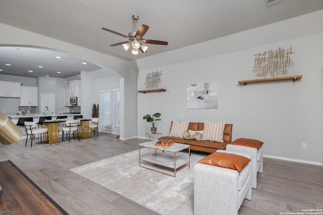 14703 Running Wolf, San Antonio, TX 78245 - living room featuring arched walkways, light wood finished floors, a ceiling fan, baseboards, and recessed lighting