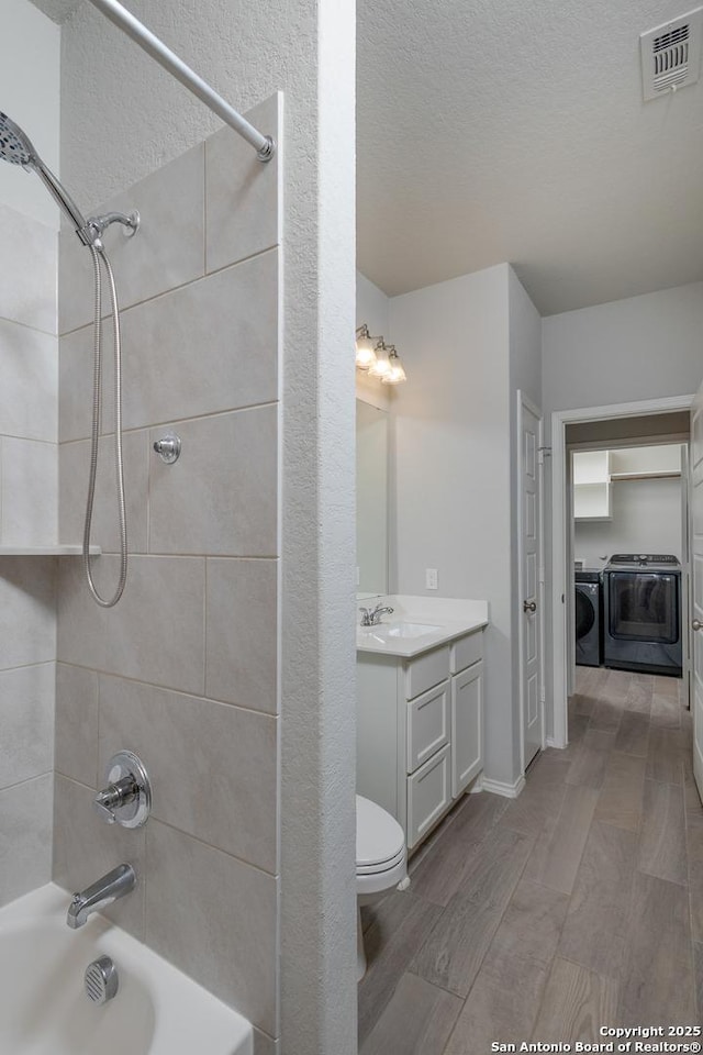 14703 Running Wolf, San Antonio, TX 78245 - bathroom with separate washer and dryer, wood finished floors, shower / bath combination, vanity, and a textured ceiling