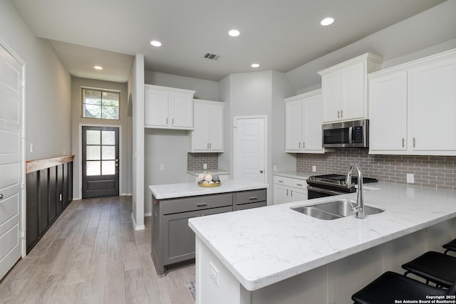 14703 Running Wolf, San Antonio, TX 78245 - kitchen with appliances with stainless steel finishes, a sink, a peninsula, decorative backsplash, and white cabinetry