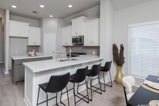14703 Running Wolf, San Antonio, TX 78245 - kitchen featuring stainless steel microwave, a peninsula, a sink, backsplash, and recessed lighting