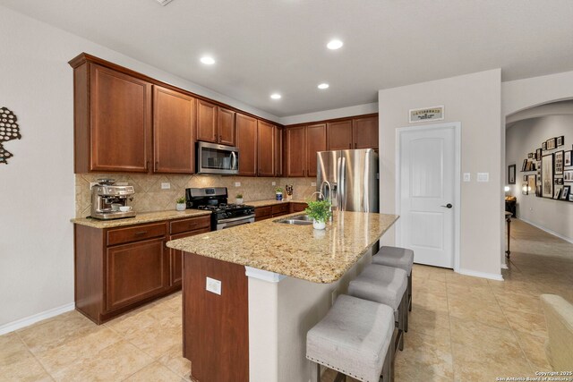 18010 Camino Del Mar, San Antonio, TX 78257 - kitchen featuring stainless steel appliances, a sink, light stone countertops, tasteful backsplash, and arched walkways