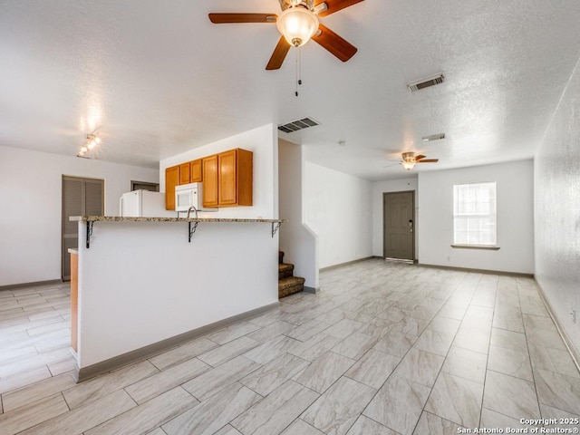 8227 Grand Bnd, San Antonio, TX 78250 - unfurnished living room with a ceiling fan, stairs, a textured ceiling, and baseboards