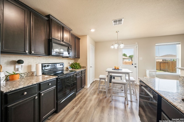 6516 Sabinal, San Antonio, TX 78252 - kitchen with black range with electric stovetop, dishwasher, light wood-style floors, a chandelier, and light stone counters