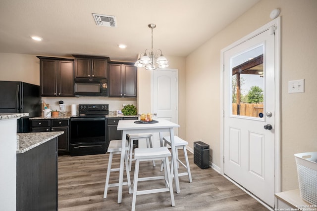 6516 Sabinal, San Antonio, TX 78252 - kitchen with black appliances, light wood-style flooring, light countertops, dark brown cabinetry, and decorative light fixtures
